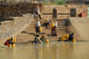 Axum - Mehakelegnaw Zone, Tigray Region: Queen of Sheba's bath - women collecting water - seen through the barbed wire - photo by M.Torres