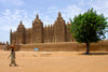 Djenn, Mopti Region, Mali: woman walking in front of Great Mosque of Djenn - UNESCO world heritage site - architect Ismaila Traor - Grande mosque de Djenn - photo by J.Pemberton