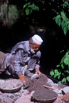 Pakistan - Murree Hills/Margalla Hills: Old mason with cement to complete a wall along a hillside road - photo by R.Zafar