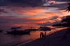 Alona Beach, Bohol island, Central Visayas, Philippines: local Banca on the beach in vivid colors - people watch the red skies - photo by S.Egeberg