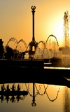 Dushanbe, Tajikistan: column with the Tajikistani national coat of arms reflected in a fountain - late afternoon sun - Parchan monument - photo by M.Torres